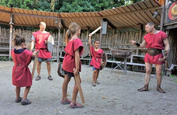 5 personnes habillées en tenue de gladiateurs en train de jouer aux gladiateurs dans une petite arène