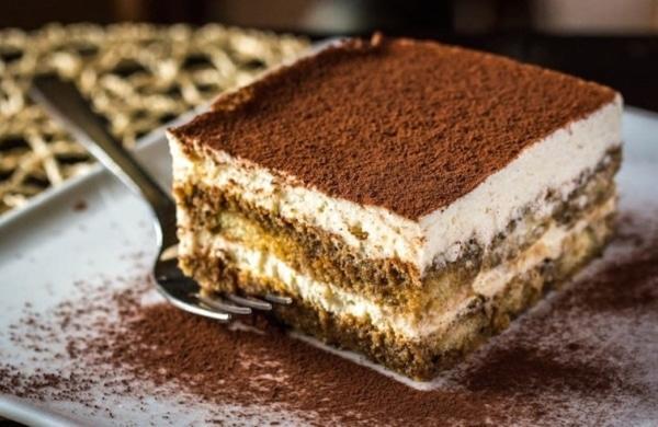 Part de tiramisu sur une assiette avec une fourchette à côté