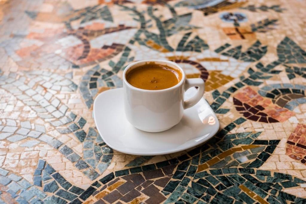 Petite tasse de café posée sur une soucoupe sur une table en mosaïque