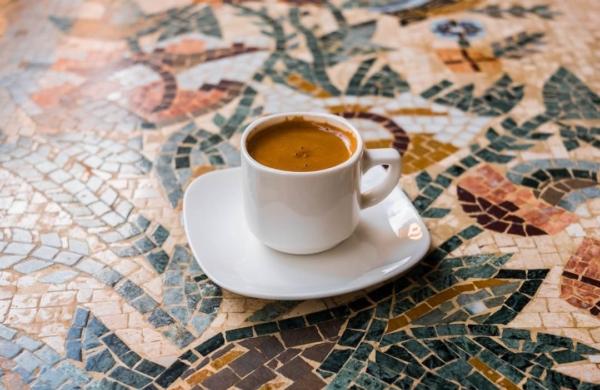 Petite tasse de café posée sur une soucoupe sur une table en mosaïque